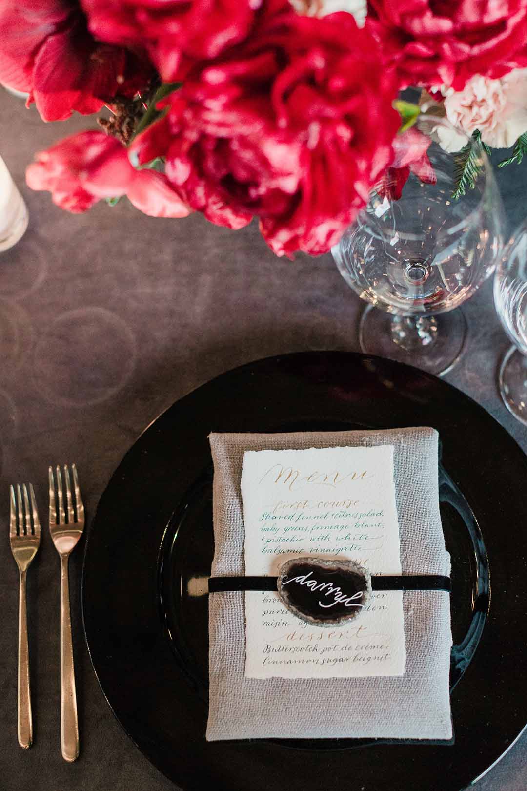 brown place-setting with purple agate name card, hand calligraphy menu, and red flowers